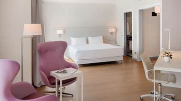 Une chambre d’hôtel avec un lit, un bureau, une chaise et une lampe sur pied.