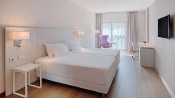 Une chambre d’hôtel moderne, dotée d’un grand lit, de tables de chevet, d’un bureau et d’une télévision.