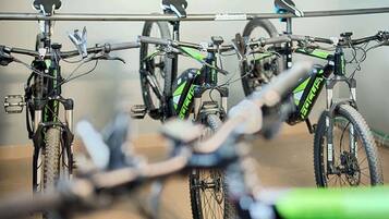 A row of bicycles parked against a wall, with a rack above them.