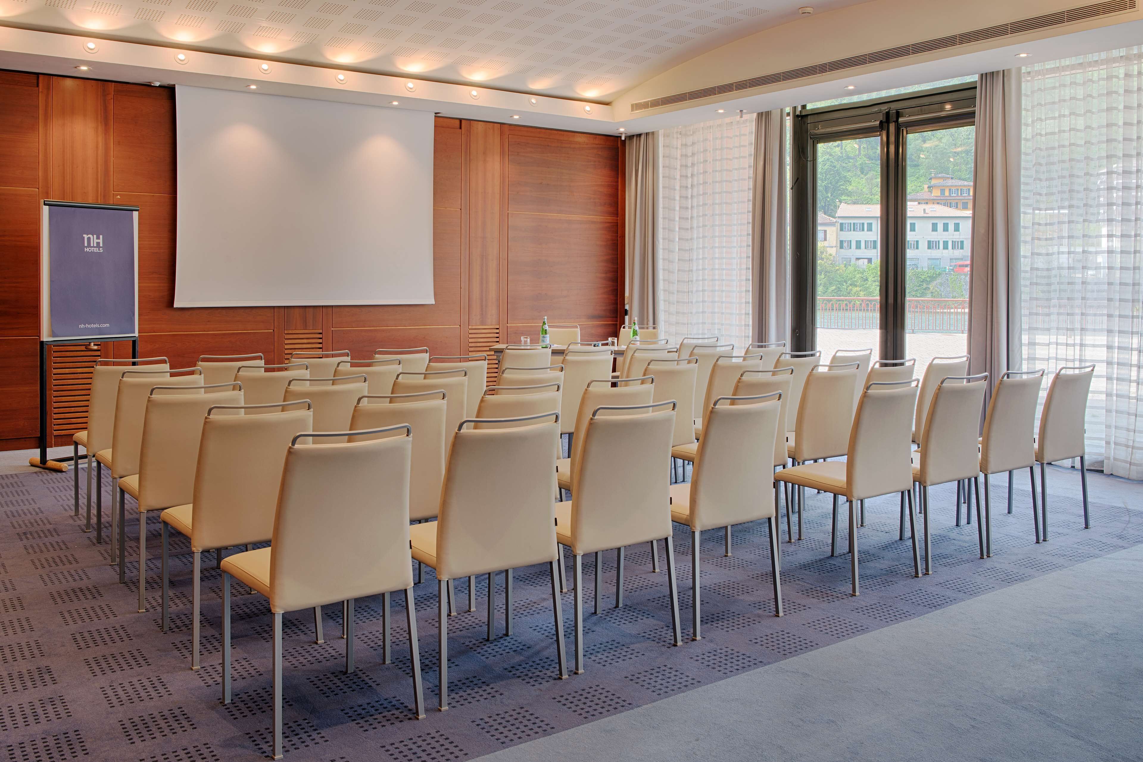 A conference room with rows of chairs, a large screen, and a projector.