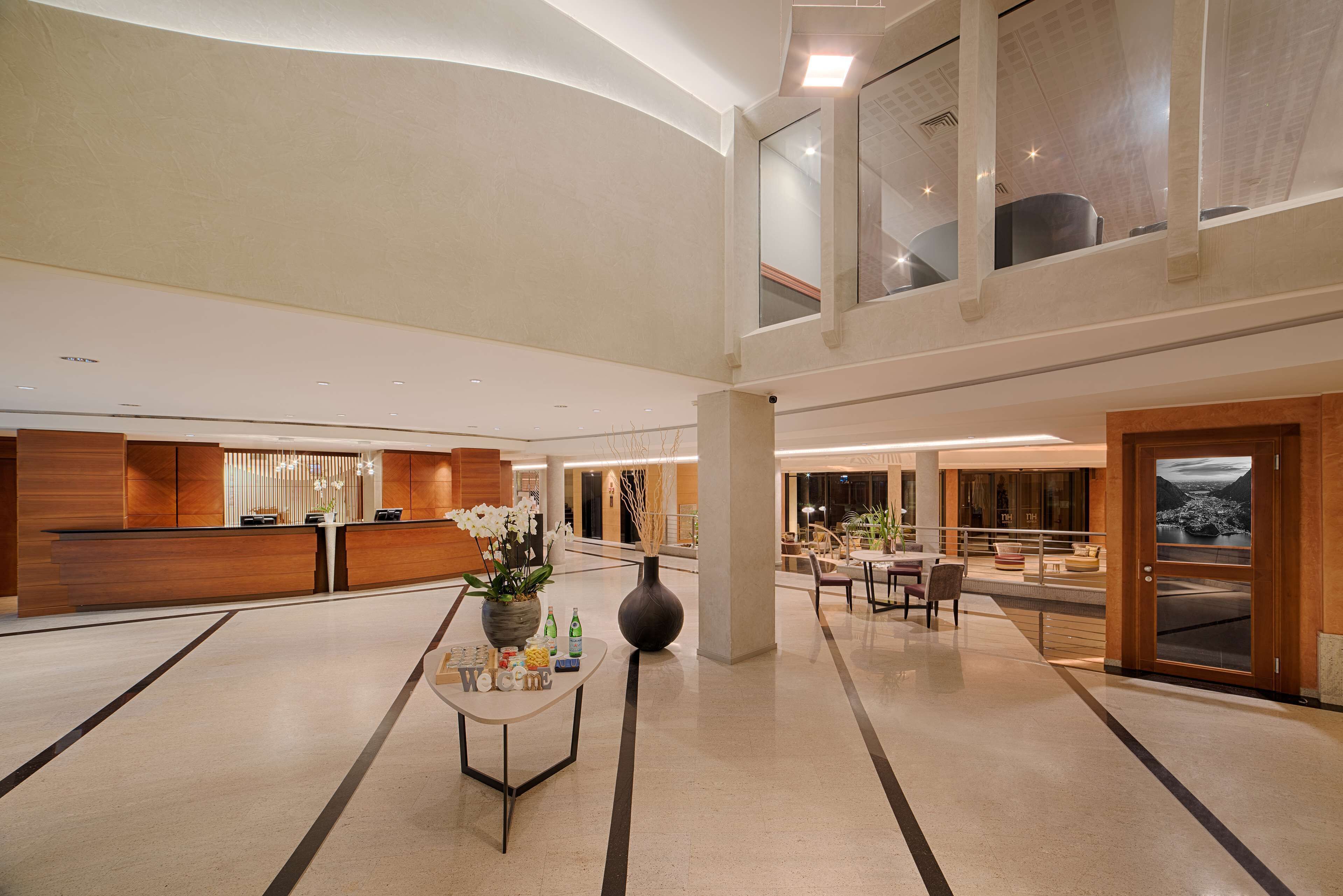 Eine großzügige Lobby mit Empfangsschalter, Sitzgelegenheiten und großen Fenstern mit Ausblick.