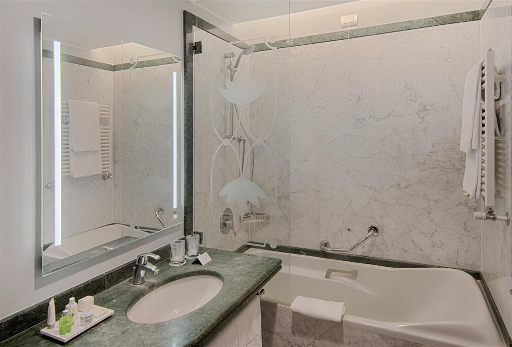 A modern bathroom with a large mirror, a sink, a bathtub, and a shower.