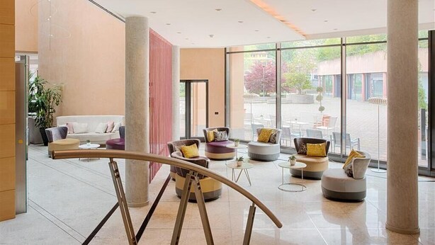 Un hall d’entrée moderne doté d’un espace salon, de grandes fenêtres et offrant une vue sur l’extérieur.