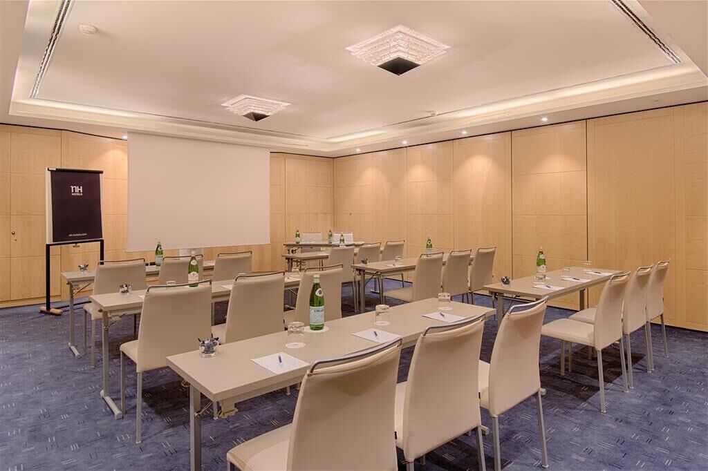 Una sala conferenze con diversi tavoli e sedie, uno schermo per proiettore e uno striscione.