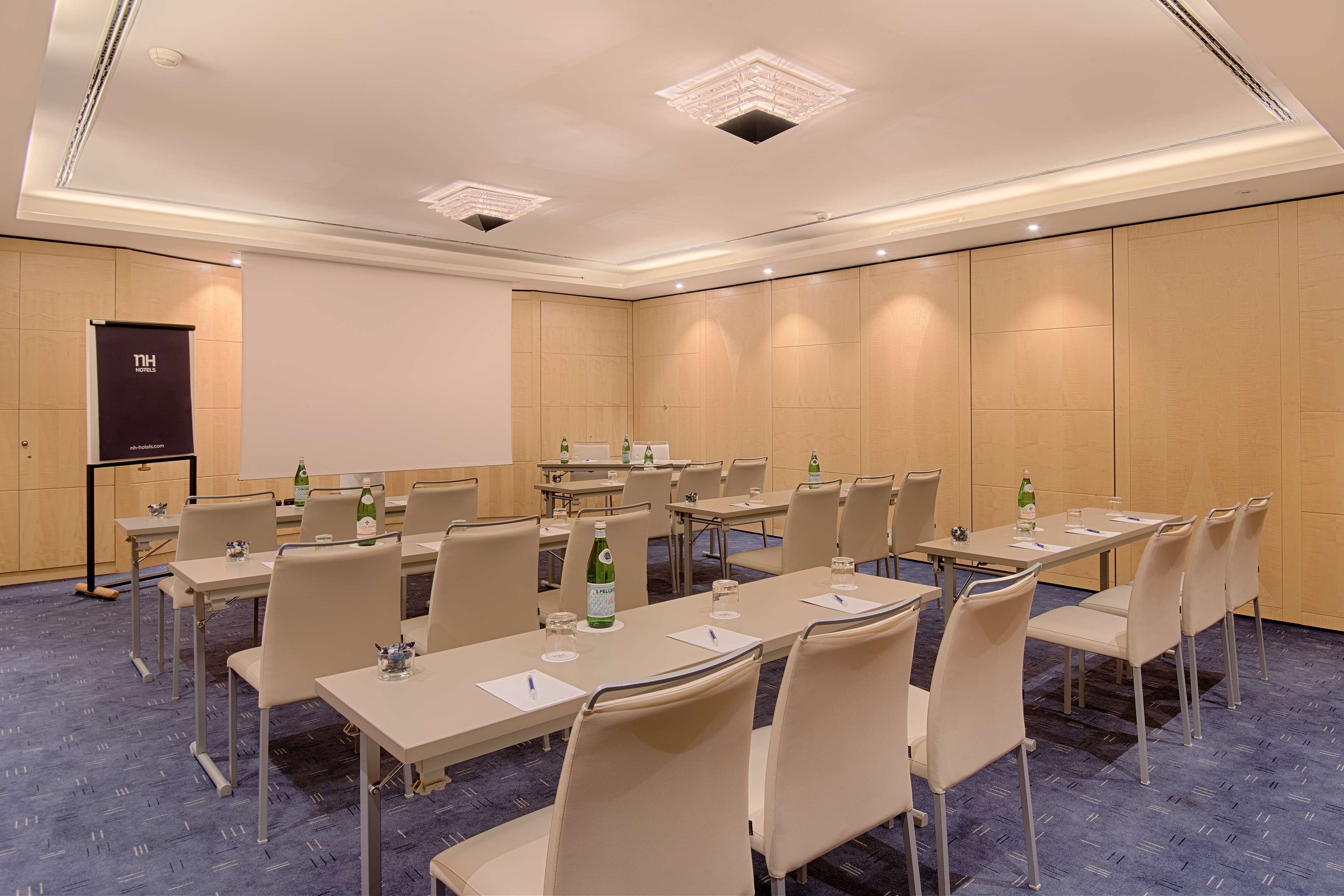 A conference room with multiple tables, chairs, and a projector screen.