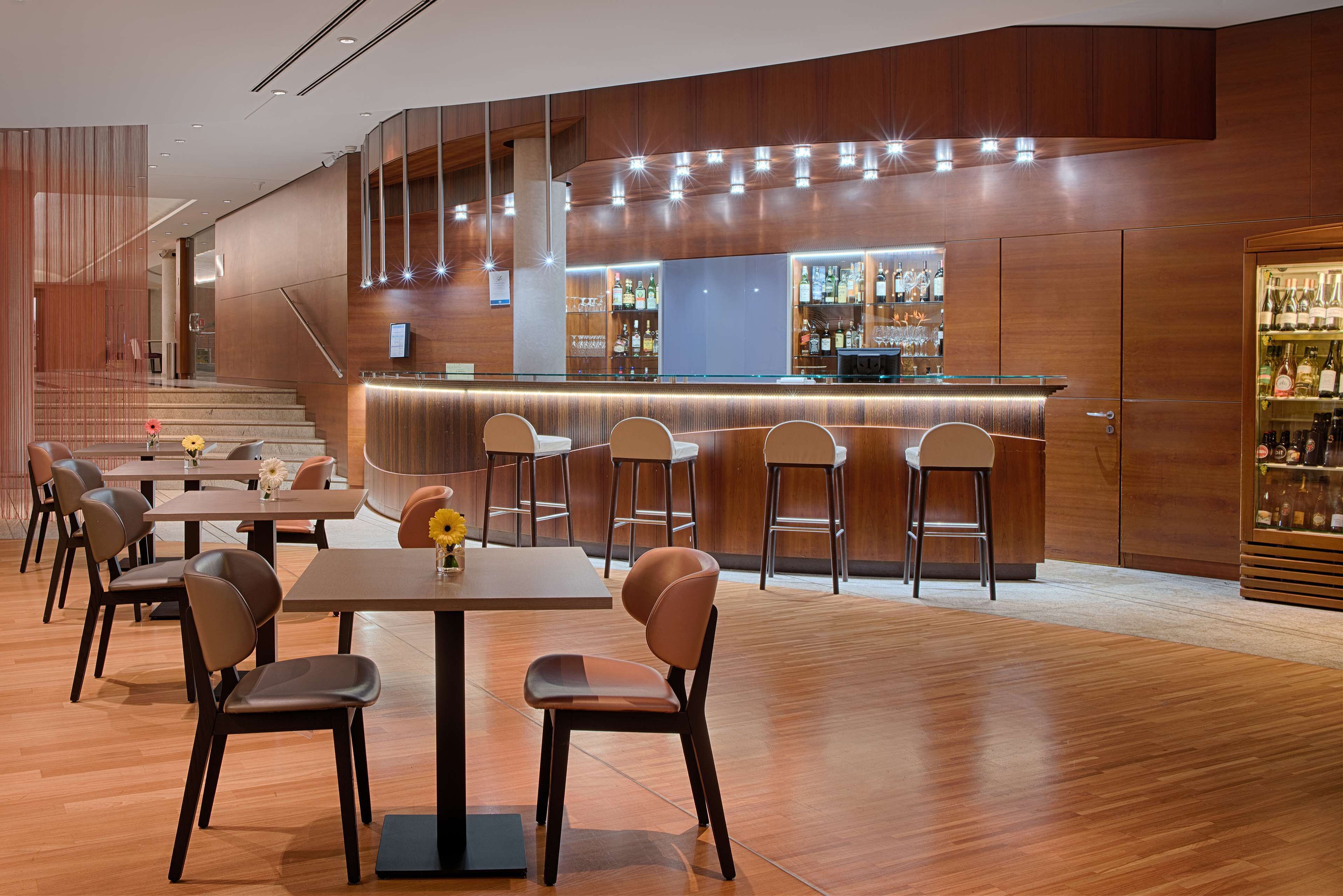 Zona de bar moderna con paneles de madera, barra y taburetes.
