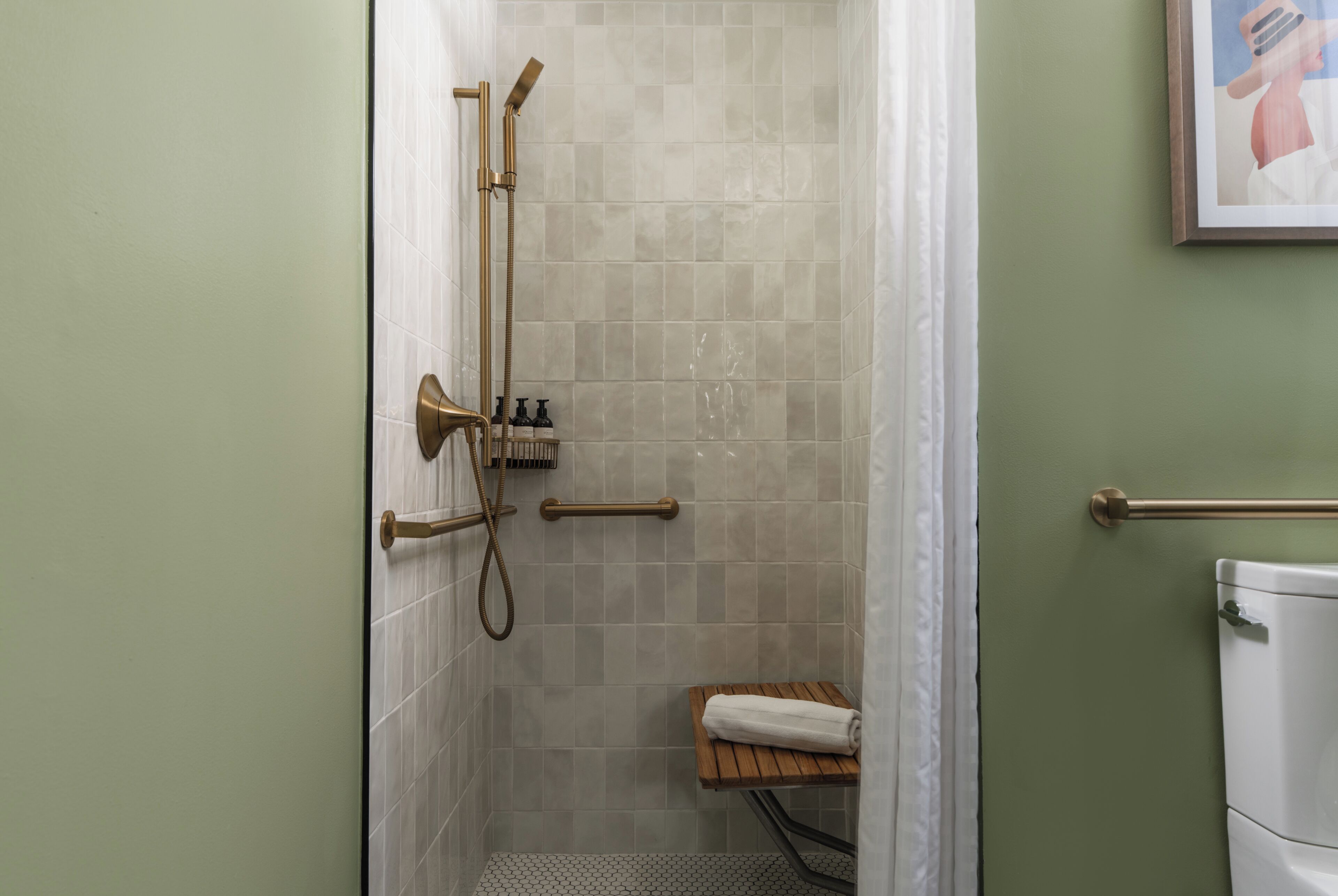 A bathroom with a shower, toilet, and a towel rack.