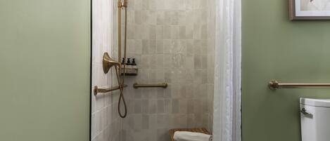 A bathroom with a shower, toilet, and a towel rack.