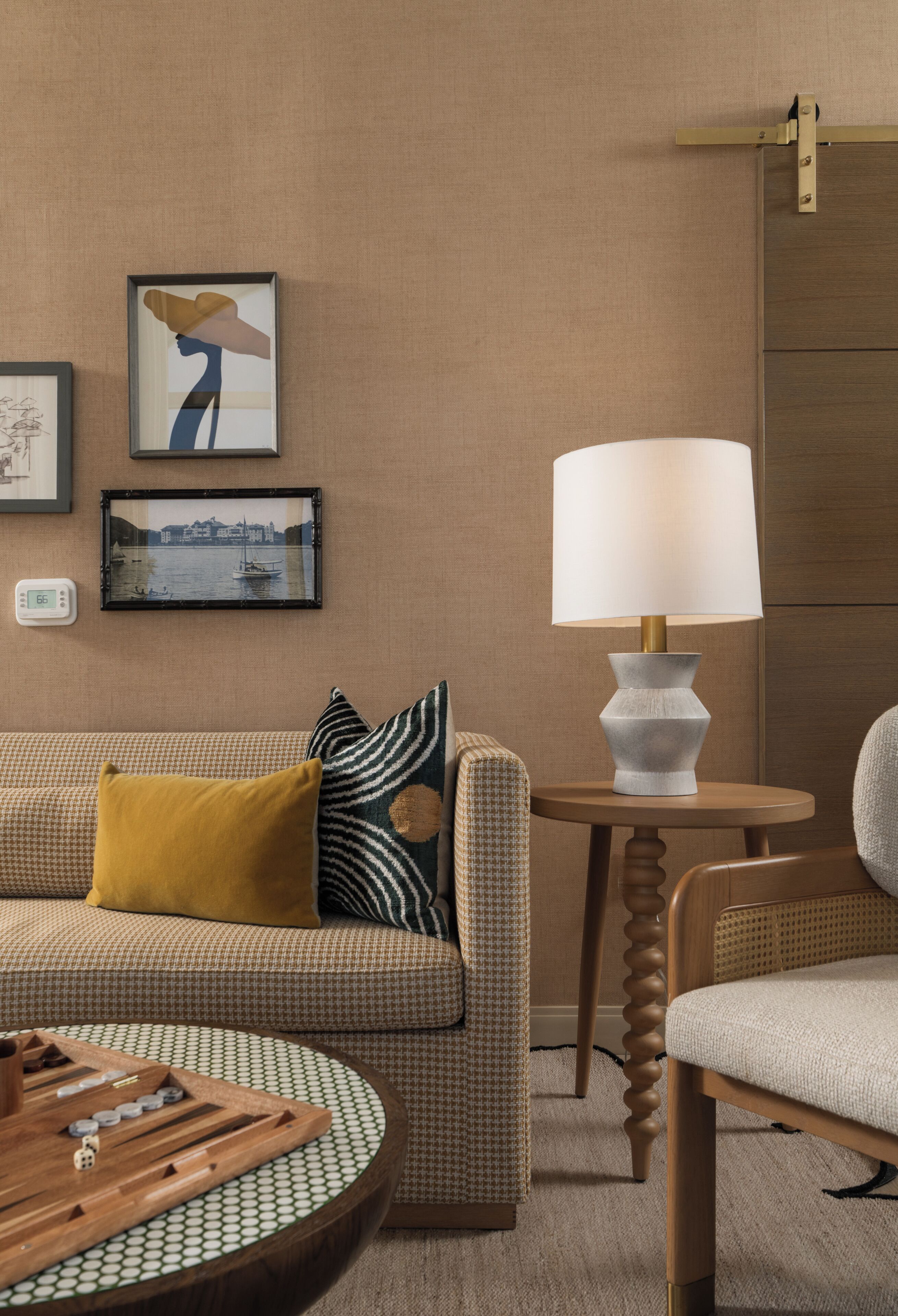 Um quarto com um sofá, uma mesa com abajur e quadros nas paredes.