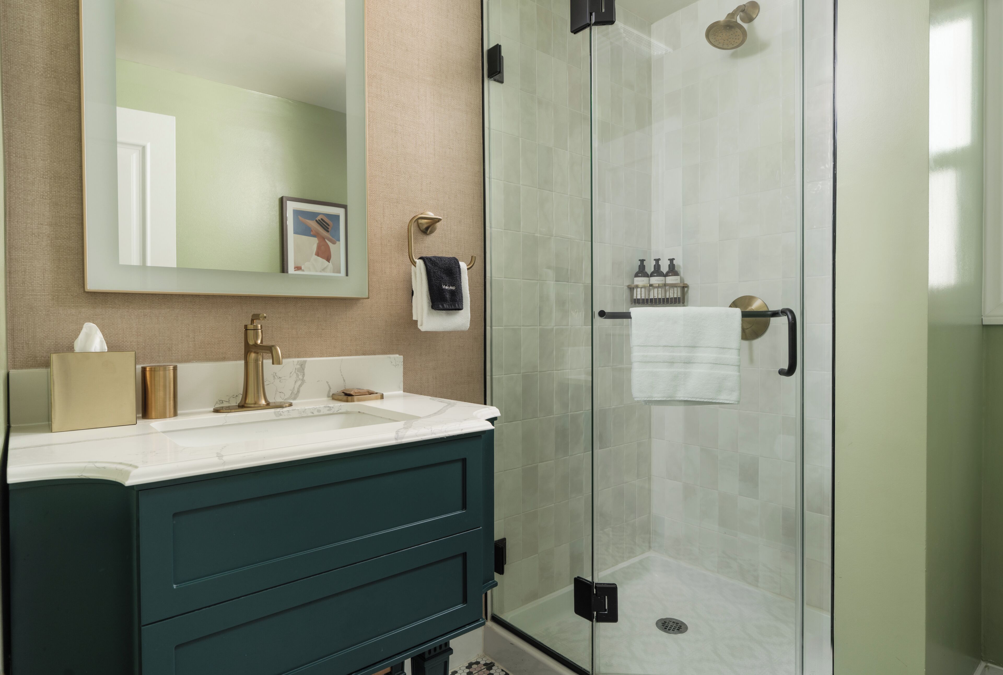 Une salle de bain moderne avec une douche à parois de verre, un meuble-lavabo doté d’un plan de travail en marbre et un grand miroir.