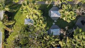 An aerial view of a courtyard with palm trees, a tiled roof, and geometric patterned seating areas.