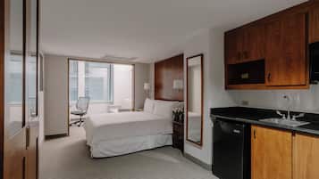 Una habitación de hotel con cama, escritorio, silla, lavamanos y espejo.