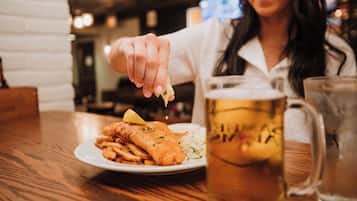 Un plato de pescado con patatas fritas y una jarra de cerveza sobre una mesa de madera.