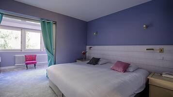 Un dormitorio con una cama grande, una mesita de noche, una silla y una ventana con cortinas.