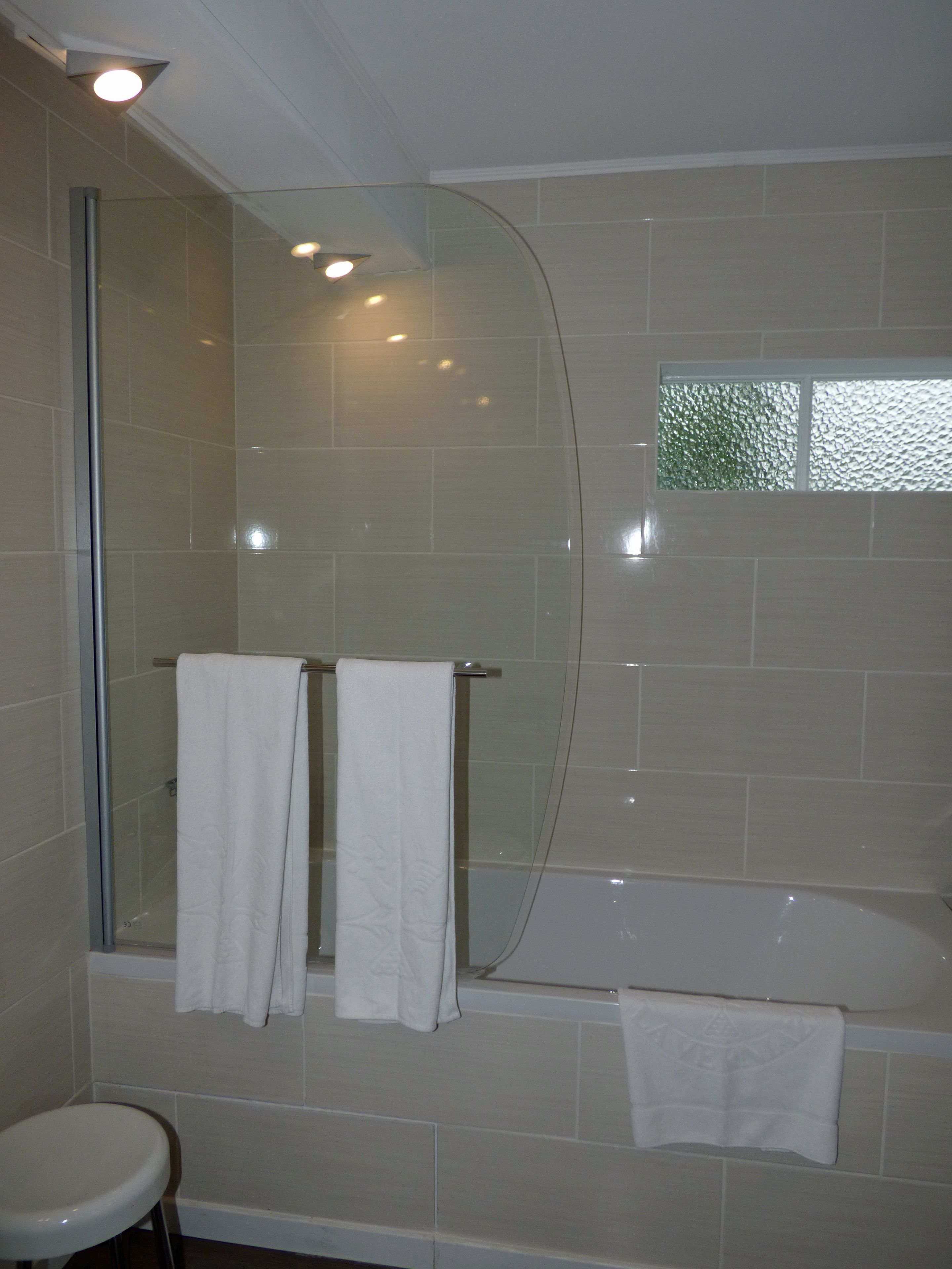 Une salle de bain avec une douche à parois de verre, une baignoire et deux serviettes blanches suspendues à un porte-serviettes.
