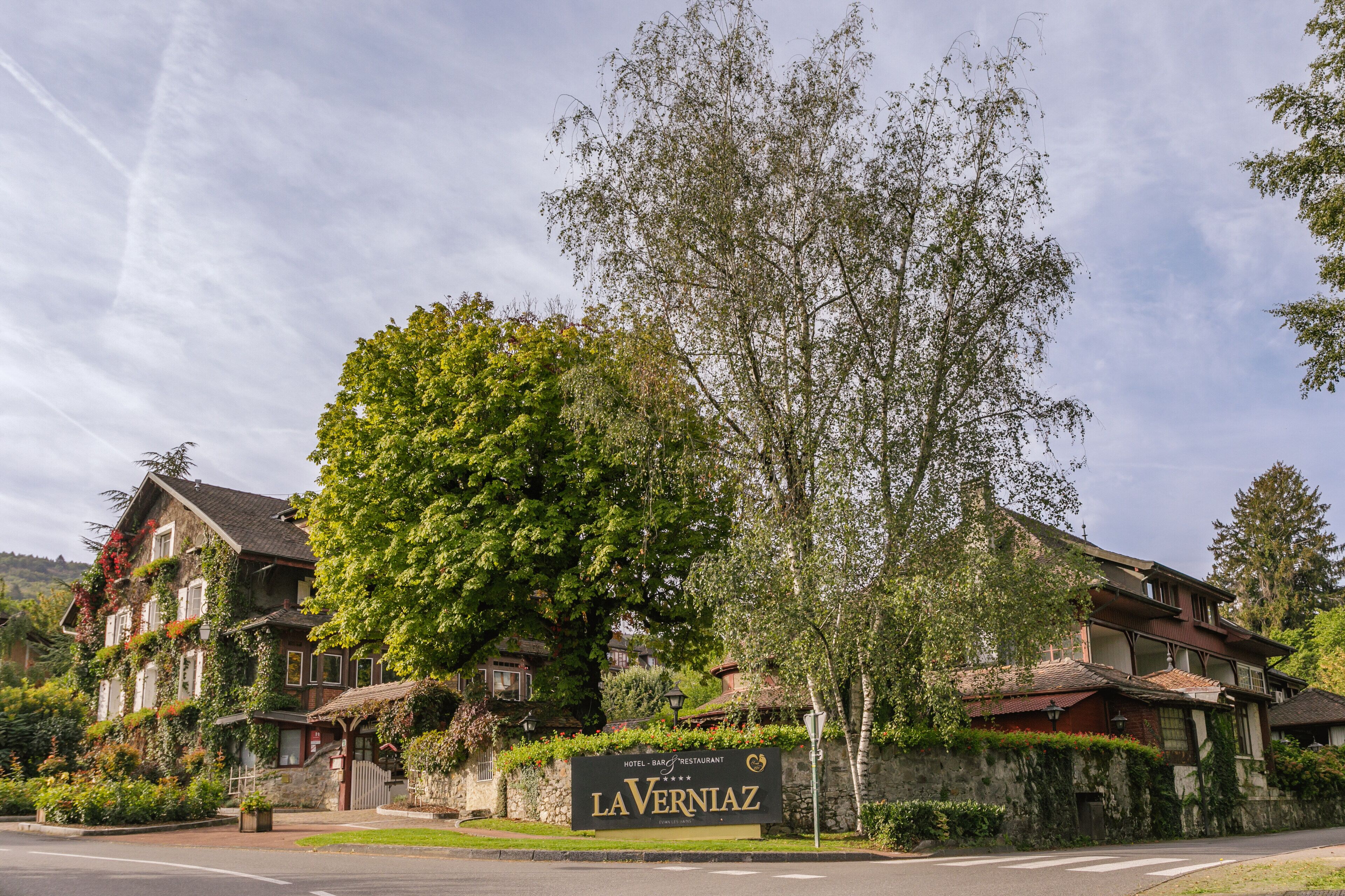 A hotel named LAVERNIAZ with a signboard, surrounded by lush greenery and trees.