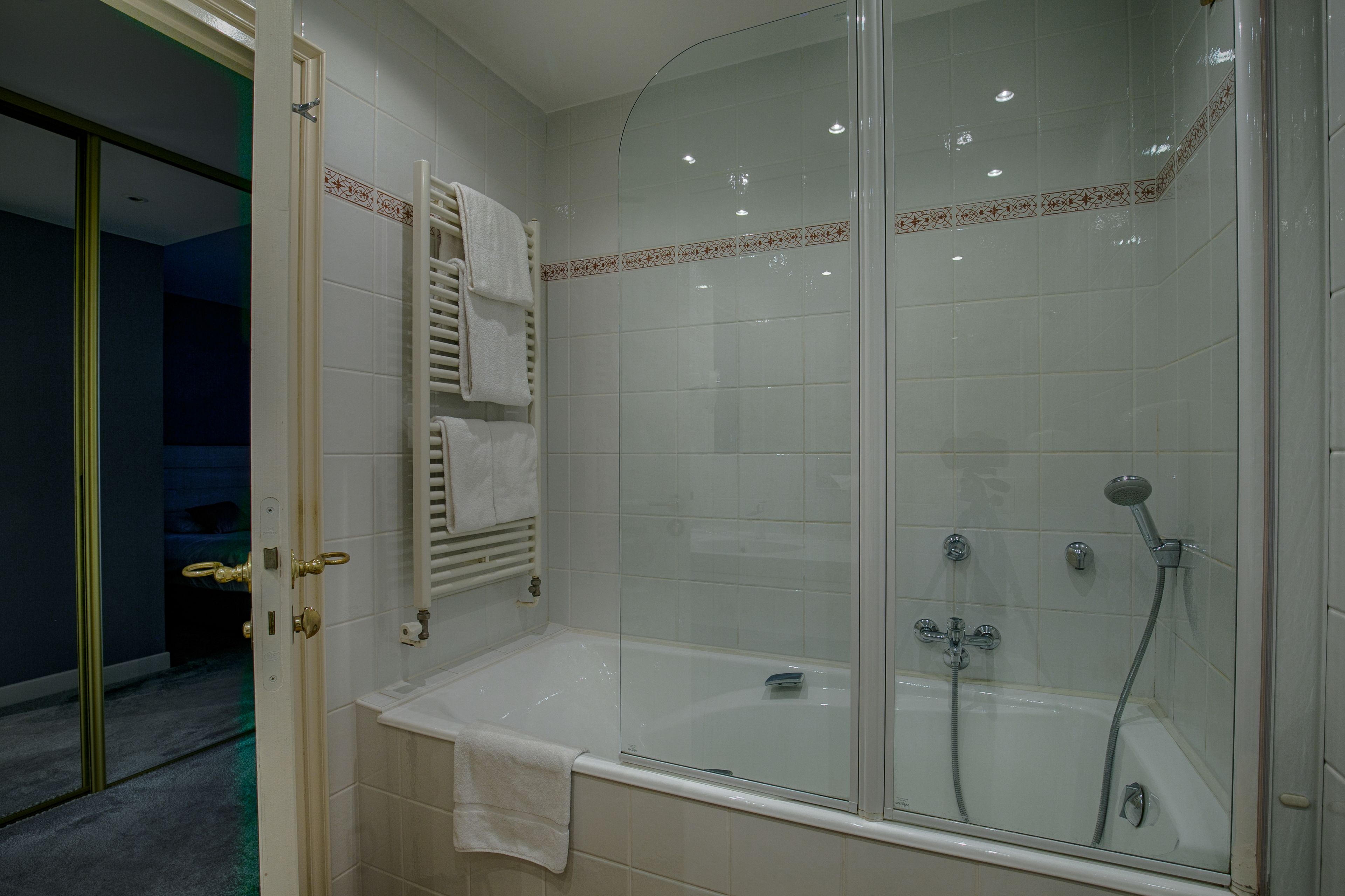 Un baño moderno con ducha de vidrio, bañera y perchero para toallas.