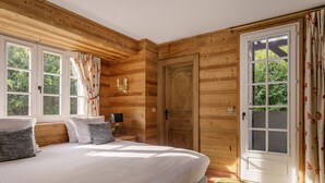 Un dormitorio con paneles de madera, una cama grande, un armario y una ventana con cortinas.