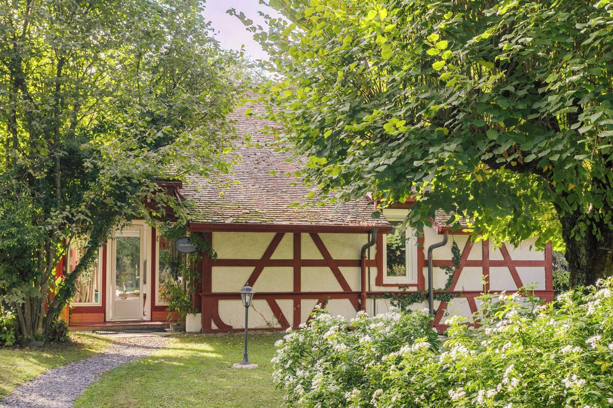 A traditional half-timbered building with a red door and a small garden area with white flowers.