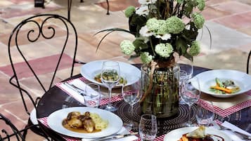 Una mesa dispuesta para una comida, con platos de comida, vasos y un florero.