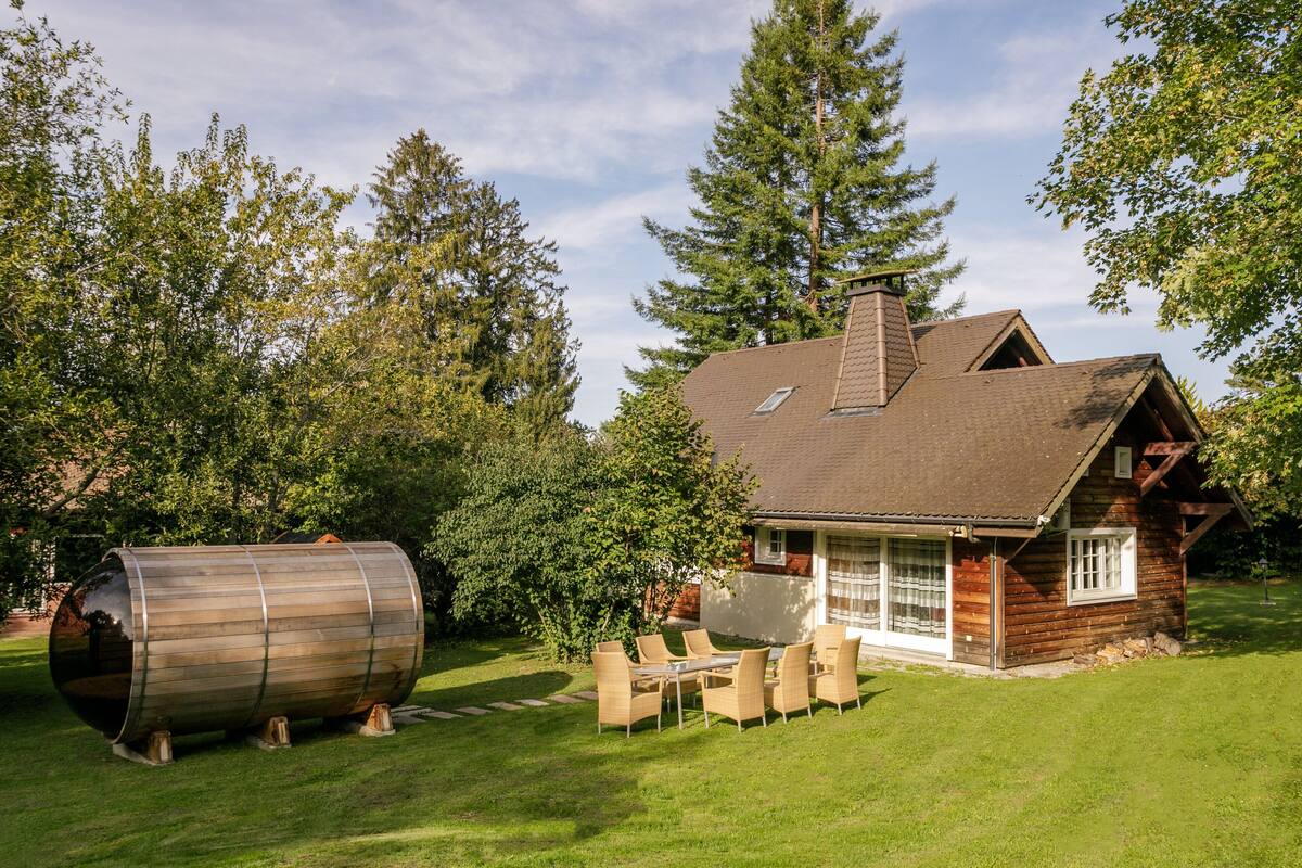 A rustic cabin with a wooden exterior, a chimney, and a dining area with outdoor furniture.