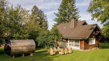 A rustic cabin with a wooden exterior, a chimney, and a dining area with outdoor furniture.