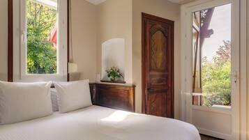 Une chambre avec un grand lit, une porte en bois et une fenêtre donnant sur un paysage verdoyant.