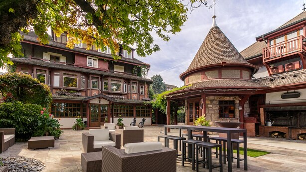 Un patio con mobiliario exterior, un pabellón y edificios tradicionales con balcones.