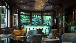 A bar area with seating and a view of the outdoors. - Le Hameau Albert 1er - Relais & Châteaux (Chamonix-Mont-Blanc)