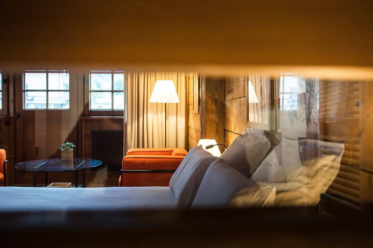Ett hotellrum med en säng, ett bord, en lampa och ett fönster.