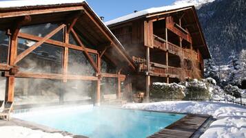 Alberca techada, alberca al aire libre y sombrillas en la alberca