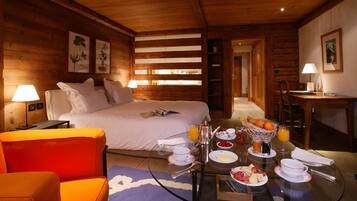 Una habitación de madera acogedora con una cama, una mesa de comedor dispuesta para el desayuno y una silla naranja brillante.