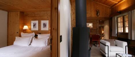 Interior de cabana de madeira com cama, sofá, lareira e quadros nas paredes.