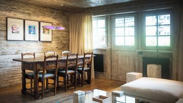 Uma sala de jantar de madeira com mesa e cadeiras, uma mesa de centro de vidro e uma lareira.
