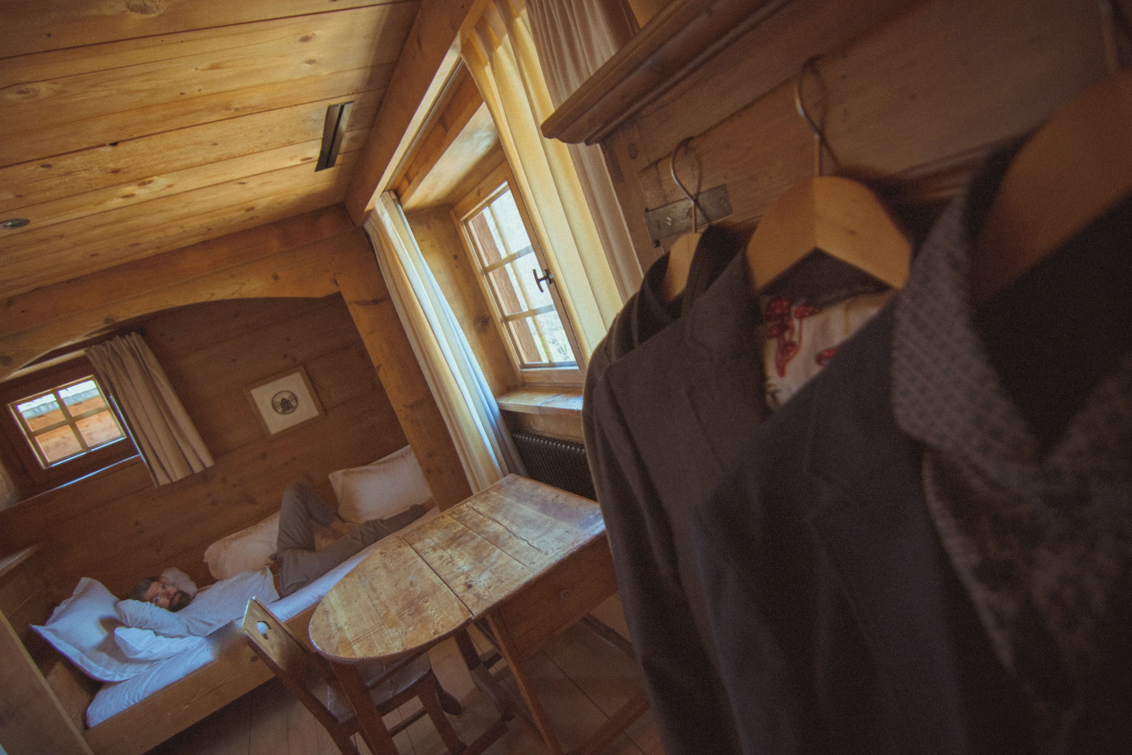 A cozy cabin with a wooden interior, a bed, a table, and a window.