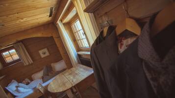 A cozy cabin with a wooden interior, a bed, a table, and a window.