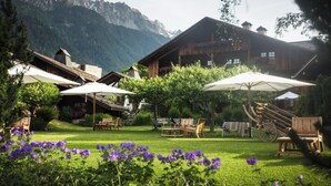 A chalet-style building with wooden architecture, outdoor seating, and a mountain backdrop. - Le Hameau Albert 1er - Relais & Châteaux (Chamonix-Mont-Blanc)