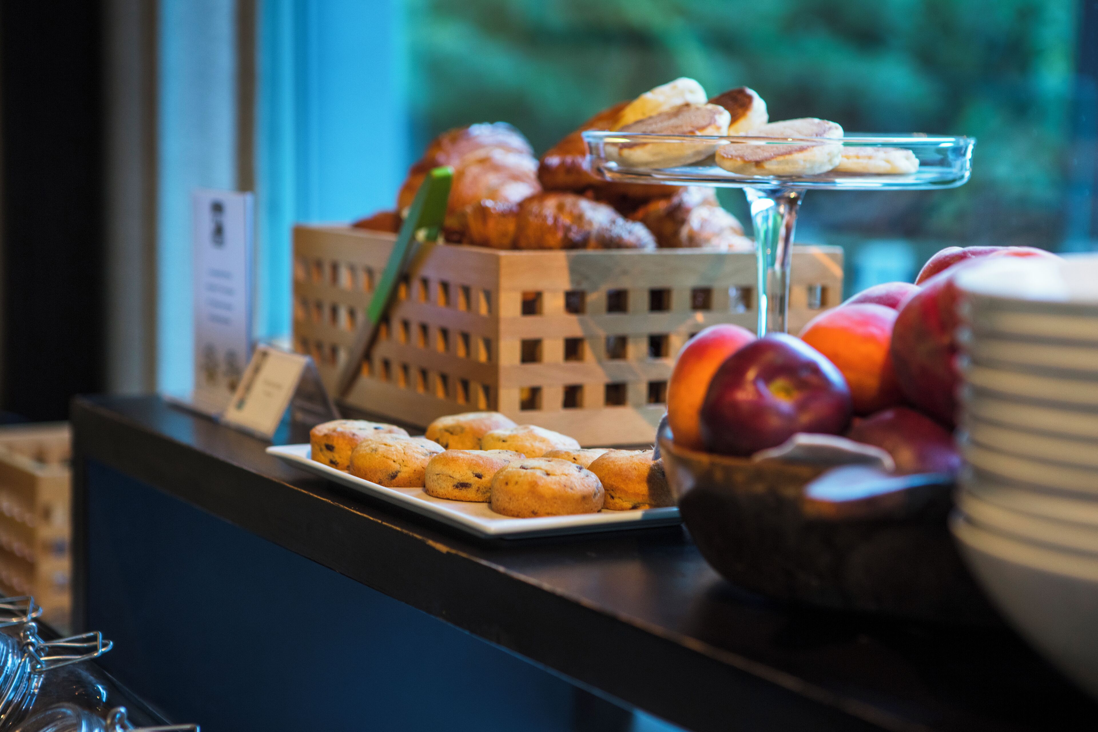 A breakfast buffet with pastries, fruits, and a glass display.