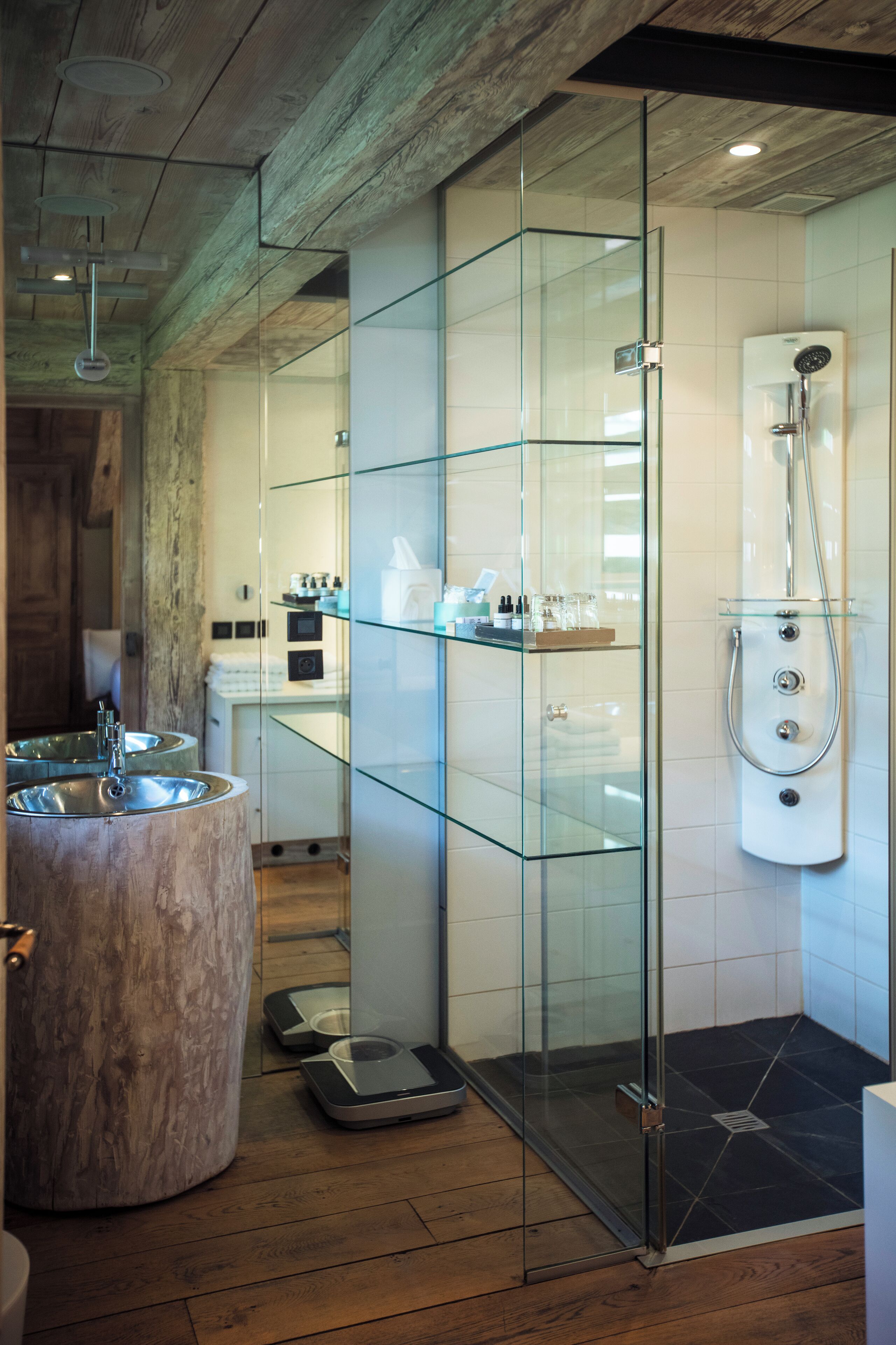 Un baño moderno con ducha de vidrio, un lavamanos grande de mármol y suelo de madera.
