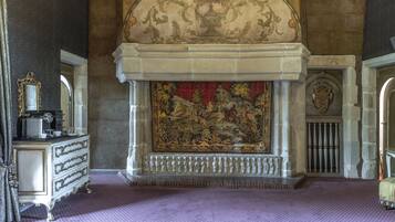 Une pièce dotée d’une cheminée, de décorations murales raffinées et d’un tapis à motifs.