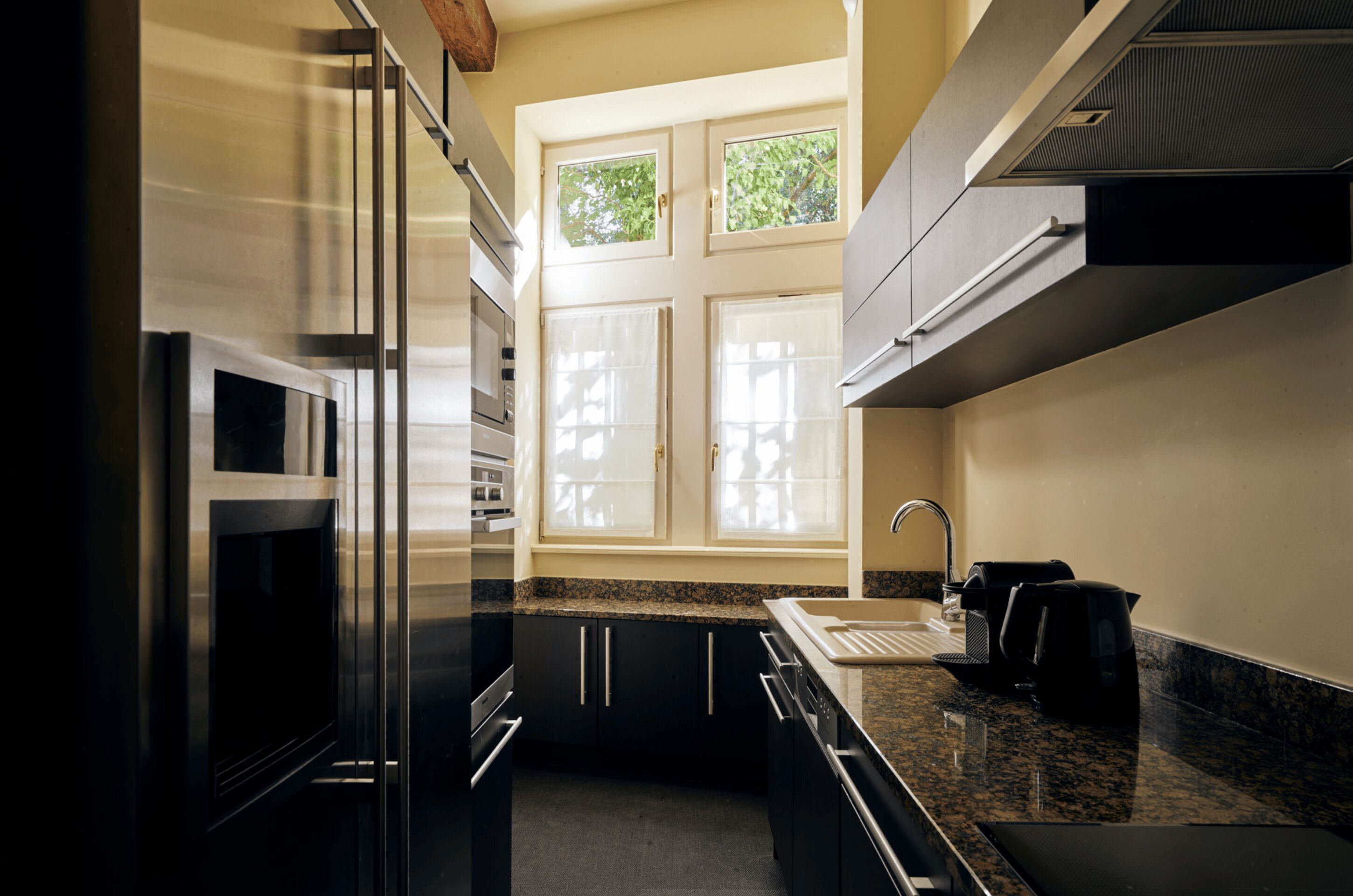 Una cucina moderna con elettrodomestici in acciaio inossidabile, un piano di lavoro in granito e una finestra che si affaccia sul verde.