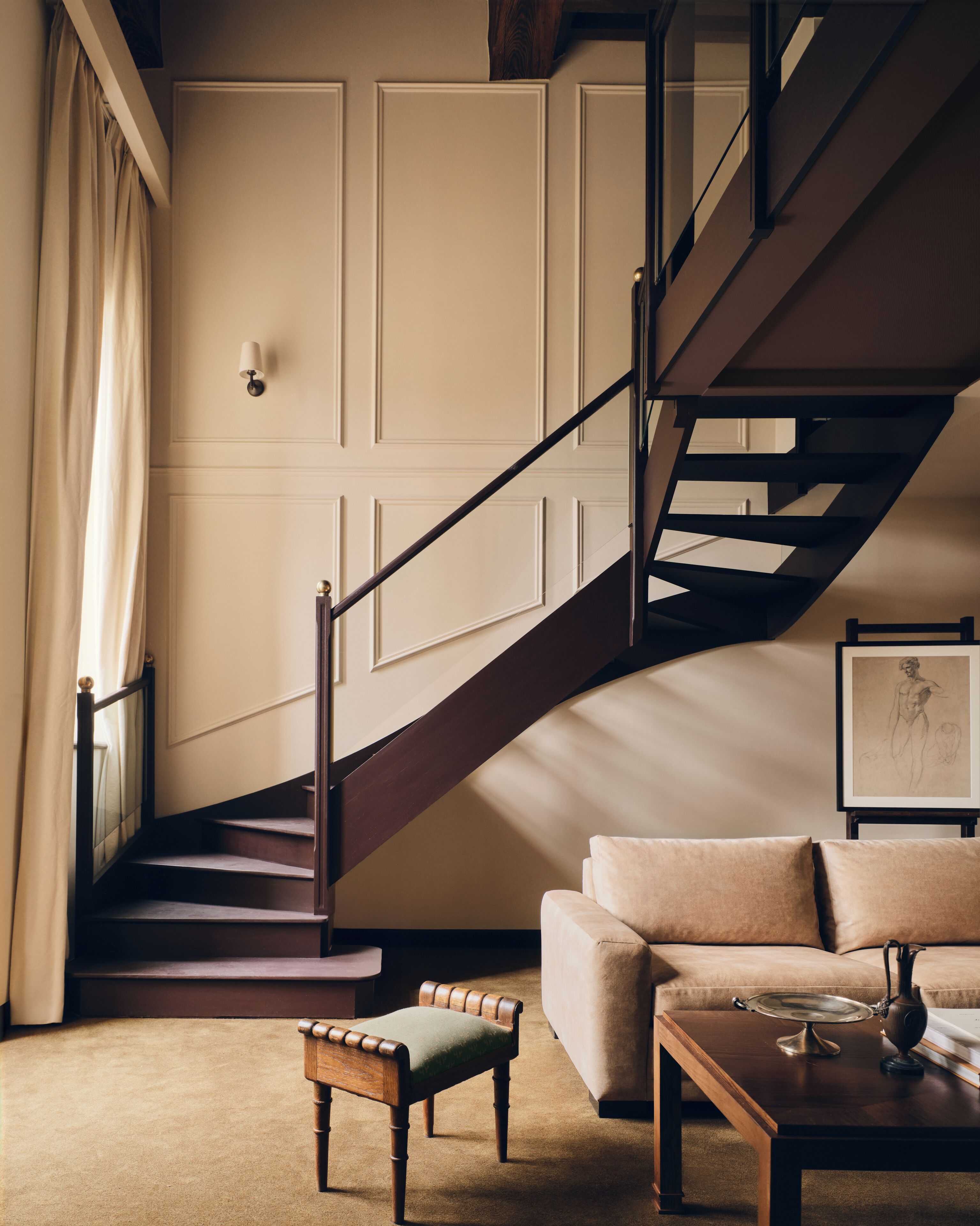 A staircase with wooden steps and a dark handrail, leading to a landing with a beige wall and a framed picture.