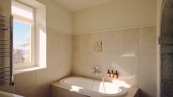 Un baño con bañera, ventana y ducha.