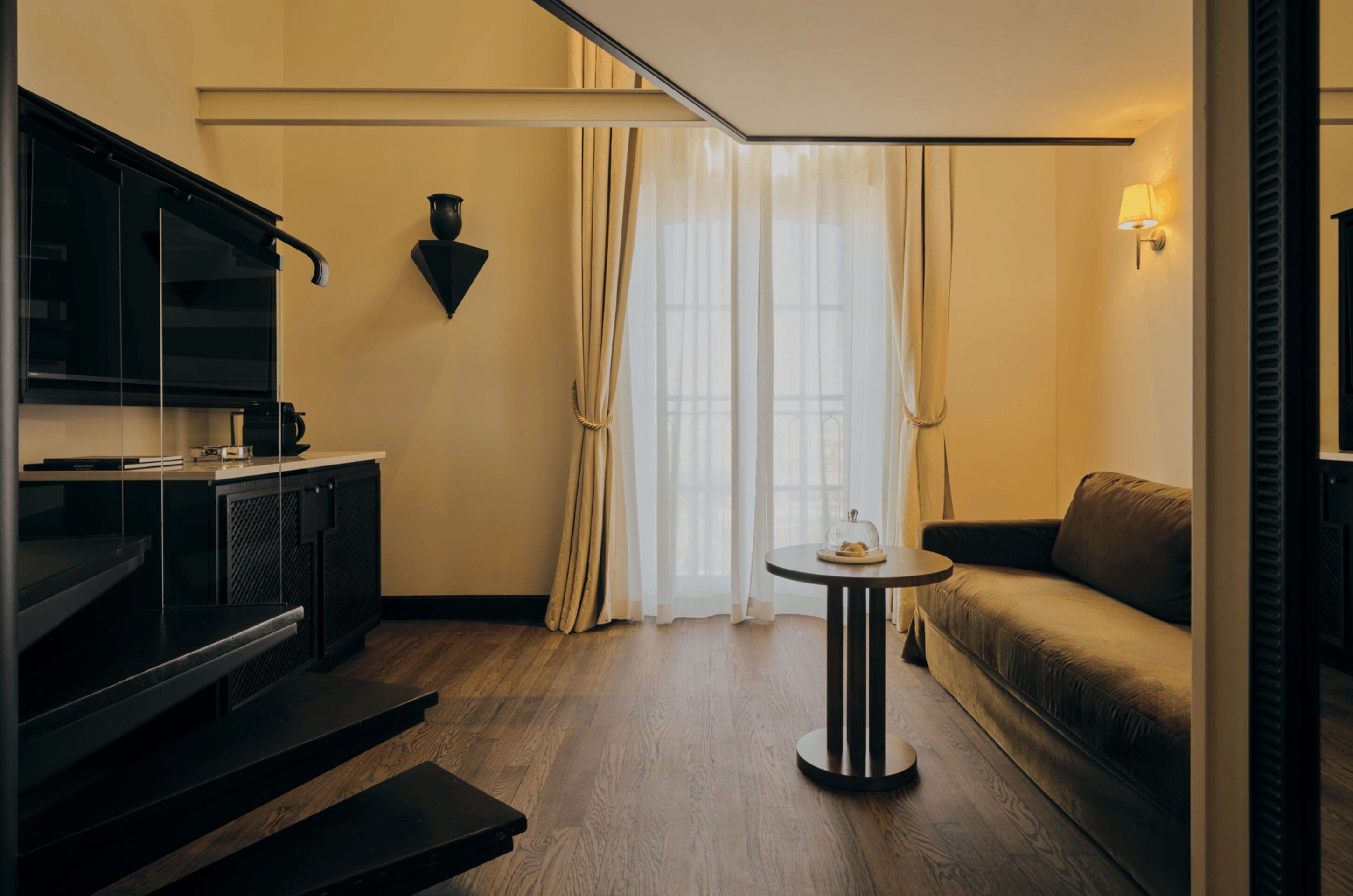 Un salon moderne avec un canapé, une table basse, un téléviseur et un escalier.