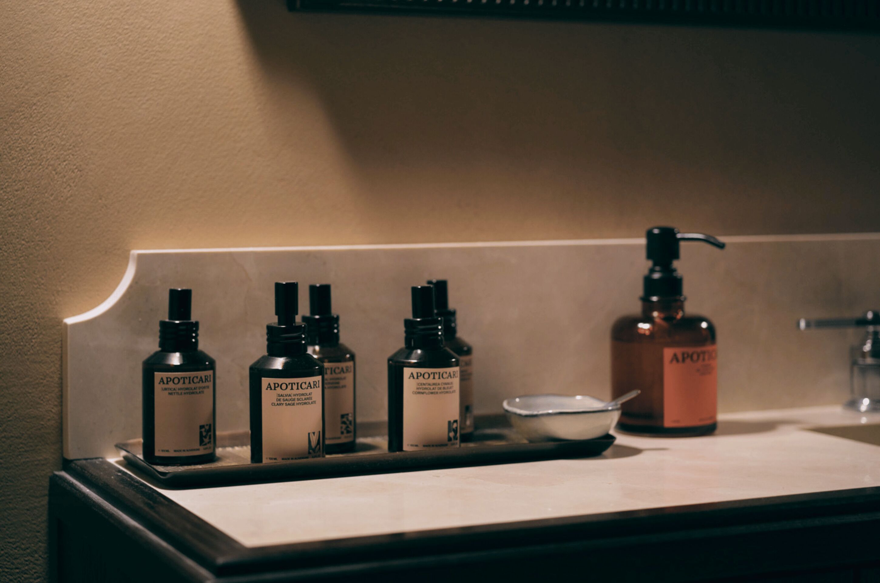 A bathroom counter with various toiletries including bottles of Apoticaris and a soap dispenser.