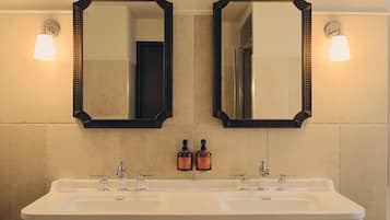 A bathroom with two mirrors, a double sink, and two bottles of hand soap.