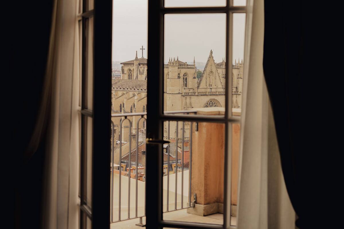 An open window with a view of a historic building with Gothic architecture.