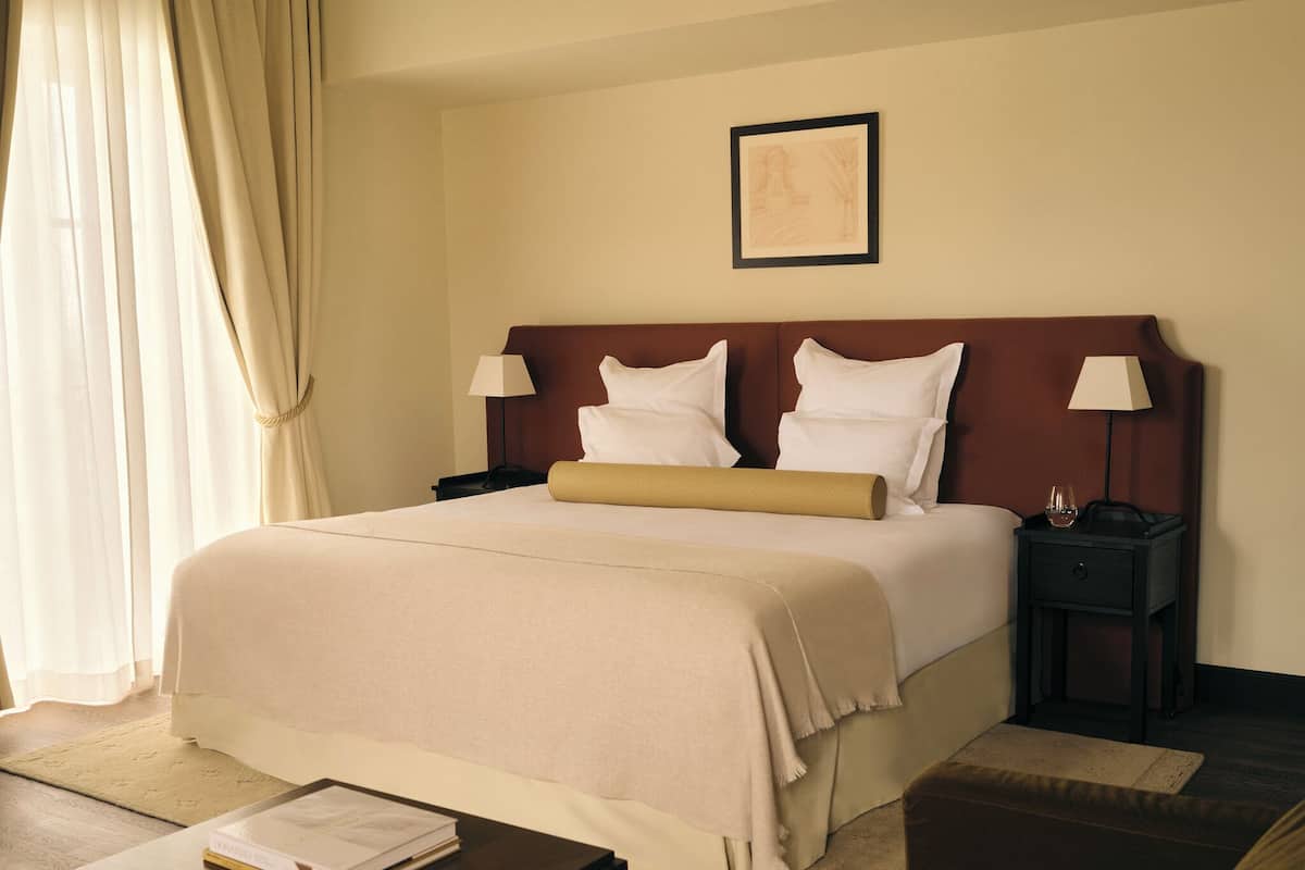 A hotel room with a large bed, two bedside tables with lamps, a framed picture on the wall, and a book on a side table.