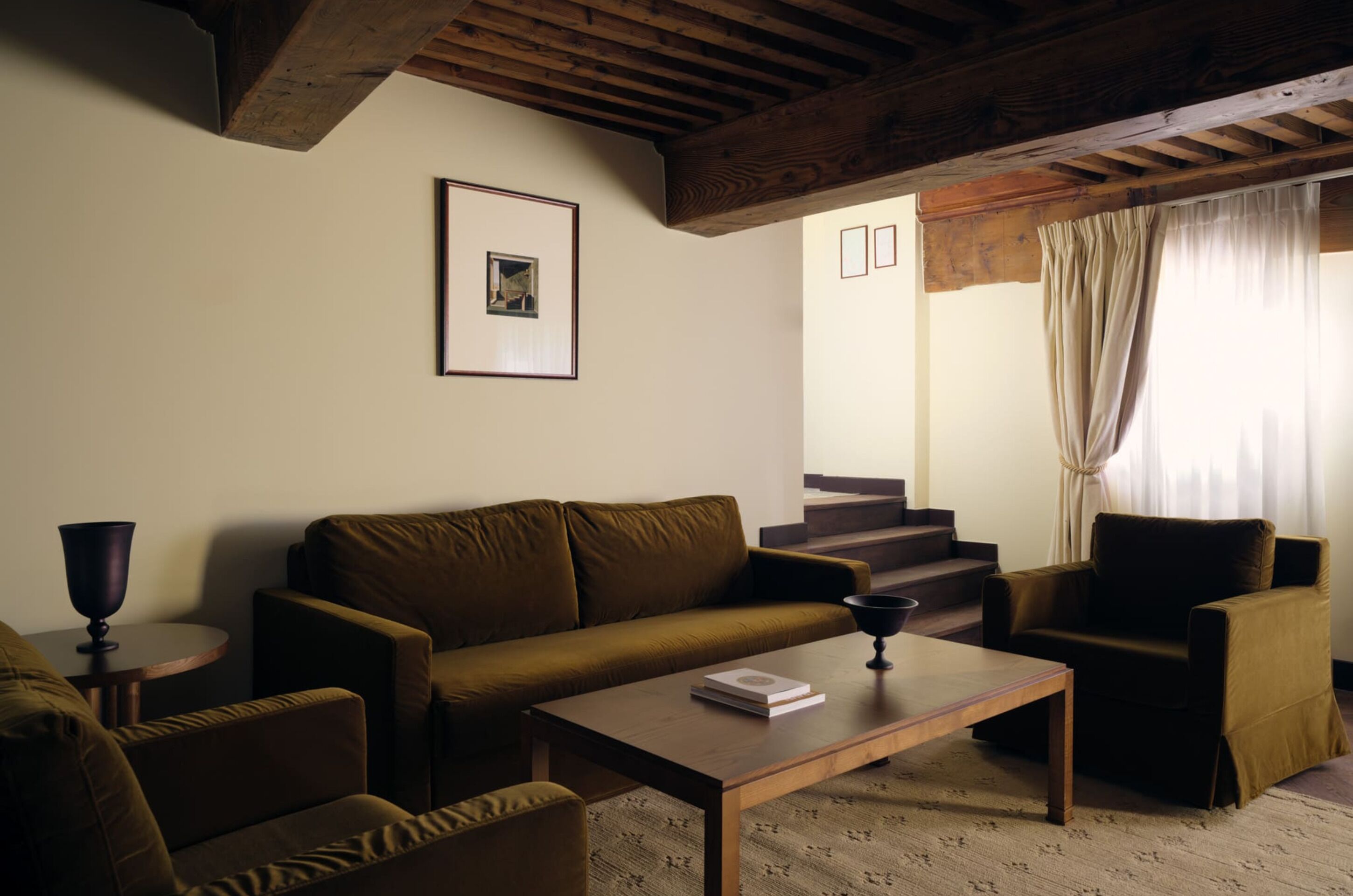 A living room with a sofa, armchair, coffee table, and a framed picture on the wall.