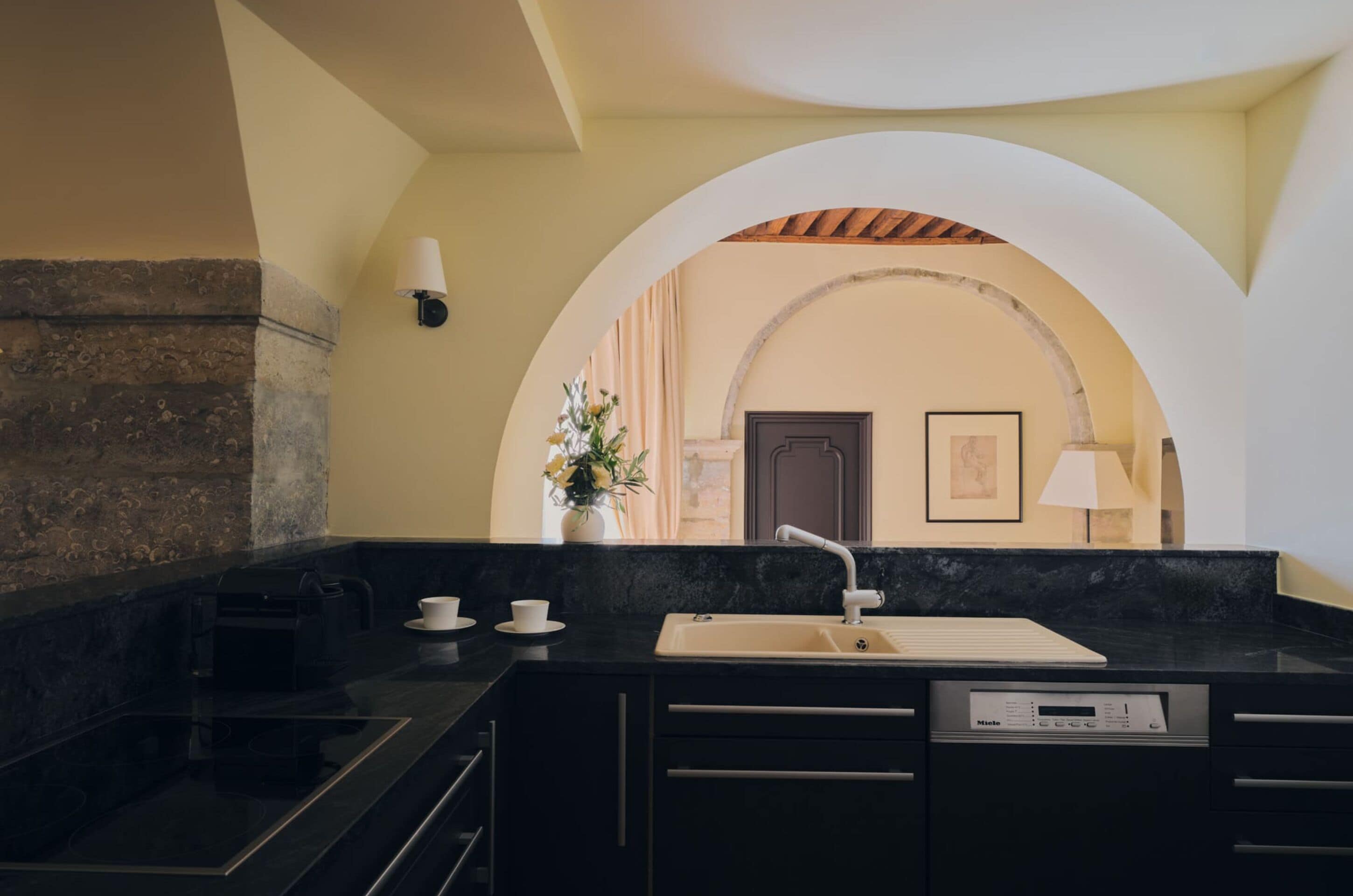 A modern kitchen with a black countertop, a built-in oven, and a sink.